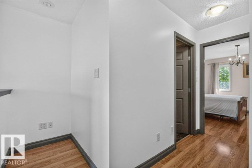 Hallway featuring wood-finish flooring, white walls, and dark trim - 21320 90 Avenue, Edmonton, AB 