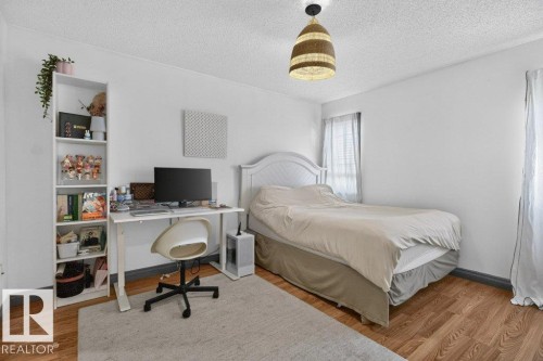 Bright room featuring wood-finish flooring, white walls, and a textured ceiling - 21320 90 Avenue, Edmonton, AB 