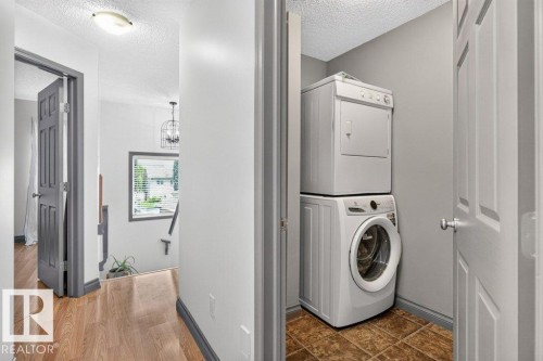 Dedicated laundry area featuring a stacked washer and dryer, complemented by patterned floor tiles - 21320 90 Avenue, Edmonton, AB 