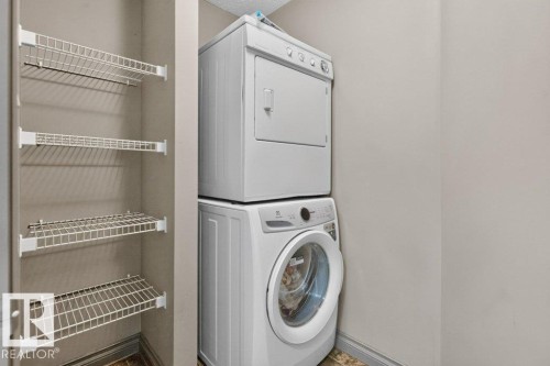 Dedicated laundry area featuring a white stacked washer and dryer unit, complemented by multi-tiered wire shelving for storage - 21320 90 Avenue, Edmonton, AB 