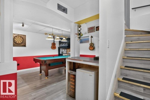 Recreation space featuring a built-in wet bar with stainless steel countertop, wood-finish flooring, and recessed lighting - 21320 90 Avenue, Edmonton, AB 