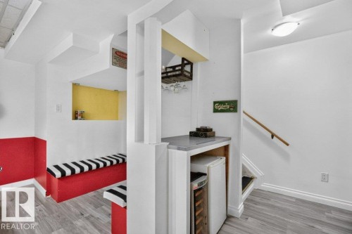 Recreational area featuring wood-finish flooring, a built-in bench with striped cushions, and a built-in bar with a countertop - 21320 90 Avenue, Edmonton, AB 