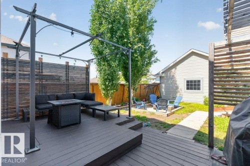 Expansive outdoor living area featuring a dark wood-finish deck with integrated seating, slatted privacy screen, and an overhead pergola structure - 21320 90 Avenue, Edmonton, AB 