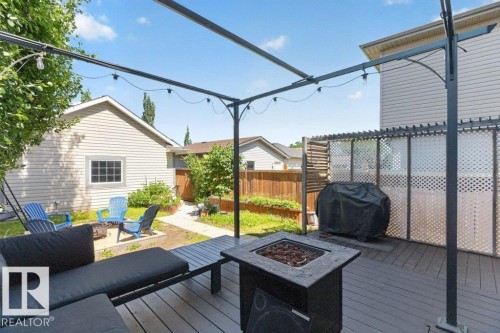 Spacious outdoor deck featuring gray composite decking, a metal pergola structure, and a built-in fire pit - 21320 90 Avenue, Edmonton, AB 