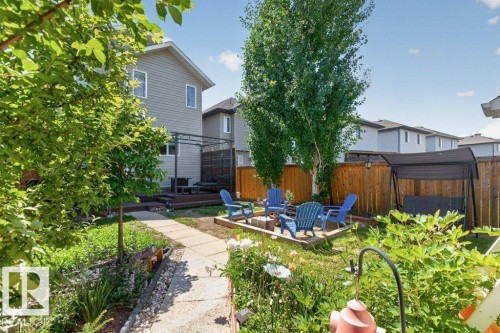 Landscaped backyard featuring a concrete pathway, a multi-level deck, a pergola structure, a wooden privacy fence, and mature trees - 21320 90 Avenue, Edmonton, AB 