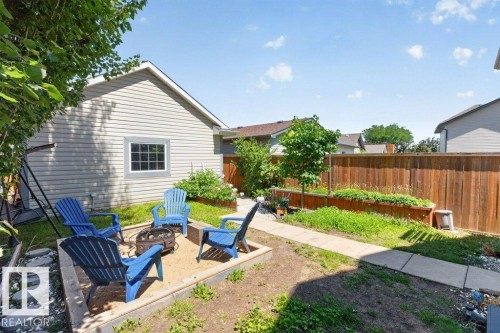 Outdoor fire pit area with an aggregate base, surrounded by established landscaping, a concrete walkway, and a full-height wood fence - 21320 90 Avenue, Edmonton, AB 
