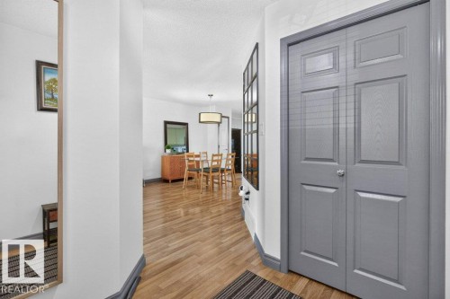 Entryway featuring wood-finish flooring, light gray bi-fold doors, white walls, and dark gray baseboards - 21320 90 Avenue, Edmonton, AB 