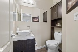 Bathroom featuring a vessel sink with a chrome faucet, dark wood-finish vanity, tiled flooring, full-width mirror, and a wall-mounted storage cabinet above the toilet - 