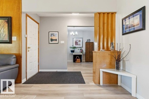 Entryway featuring wood-finish flooring, a paneled front door, and a decorative wood screen - 10235 74 Street, Edmonton, AB 