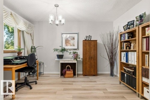 Light wood-finish flooring complements the neutral wall color in this versatile room - 10235 74 Street, Edmonton, AB 