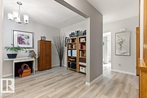 Light wood-finish flooring extending through the entry and corridor - 10235 74 Street, Edmonton, AB 