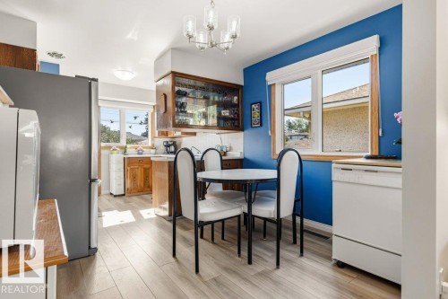 Bright kitchen space featuring wood-finish flooring, a white tile backsplash, and a built-in display cabinet with glass doors - 10235 74 Street, Edmonton, AB 