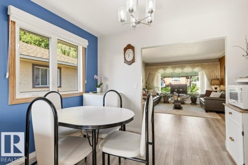 Hardwood-finish flooring extending from the dining area into an open archway - 10235 74 Street, Edmonton, AB 