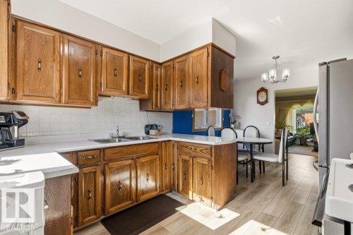 Kitchen featuring wood cabinetry, white countertops, dual basin sink, and a white tile backsplash - 10235 74 Street, Edmonton, AB 