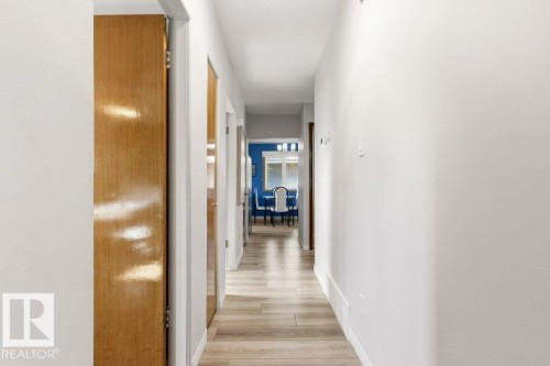 Hallway featuring wood-finish flooring, white walls, and wood doors - 10235 74 Street, Edmonton, AB 