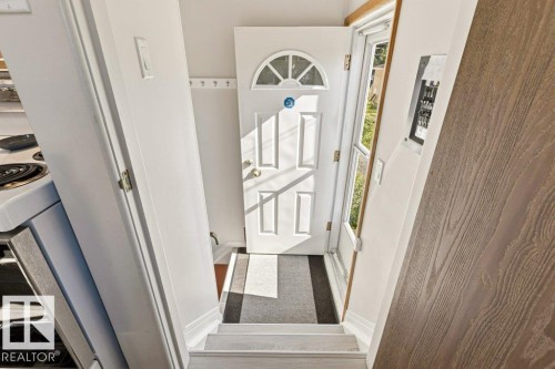Entryway featuring a paneled door with an arched transom window, a storm door, and a built-in coat rack - 10235 74 Street, Edmonton, AB 