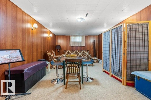 Spacious room featuring wood paneling, sconce lighting, and a neutral carpet - 10235 74 Street, Edmonton, AB 