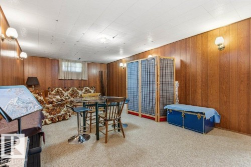 Room featuring wood-paneled walls, carpeted flooring, and a drop ceiling with integrated lighting - 10235 74 Street, Edmonton, AB 