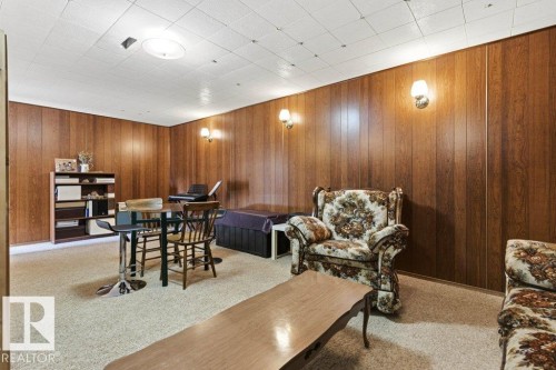 Recreational room featuring wood paneling, drop ceiling with recessed lighting, wall-mounted sconces, and neutral carpet flooring - 10235 74 Street, Edmonton, AB 