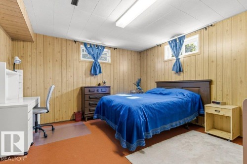 Wood-paneled room featuring two windows and a white ceiling with a rectangular fluorescent light fixture - 10235 74 Street, Edmonton, AB 