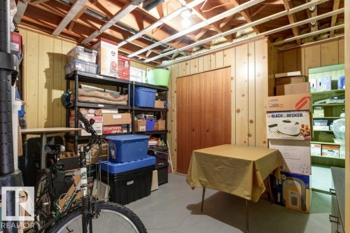 Finished basement area featuring paneling, exposed ceiling joists, and a bi-fold closet door - 10235 74 Street, Edmonton, AB 