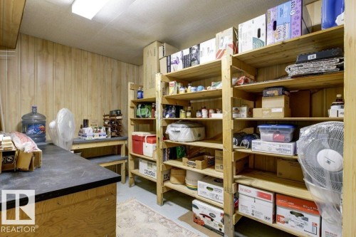 Functional utility room with extensive built-in wooden shelving, a work surface, and light wood-finish wall paneling - 10235 74 Street, Edmonton, AB 