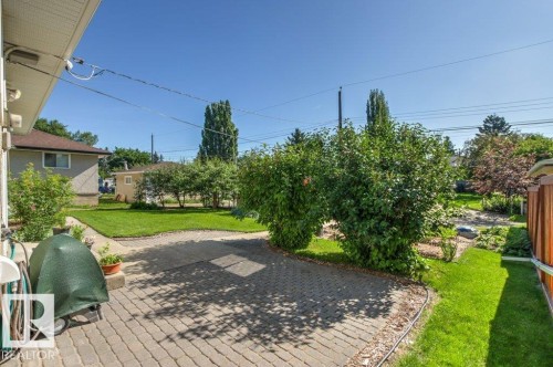 Expansive backyard featuring a paver patio, a manicured lawn, and mature perimeter landscaping - 10235 74 Street, Edmonton, AB 