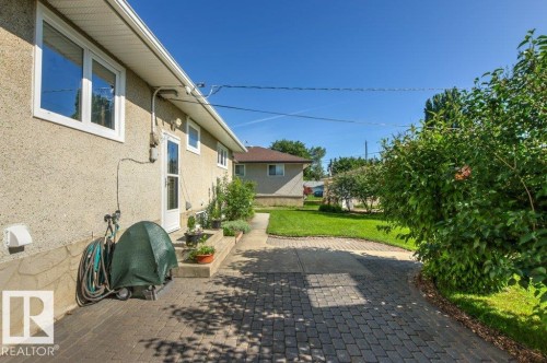 Exterior featuring a stucco finish, multiple windows, and a side entry door - 10235 74 Street, Edmonton, AB 