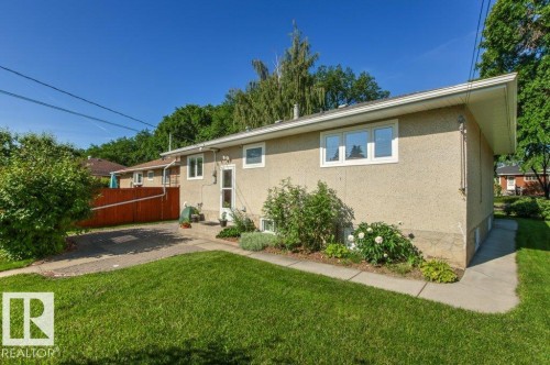Exterior stucco finish with white-trimmed windows and a side entry door - 10235 74 Street, Edmonton, AB 