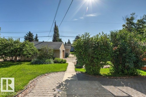 Stucco exterior with a dark shingle roof and a separate garage structure - 10235 74 Street, Edmonton, AB 