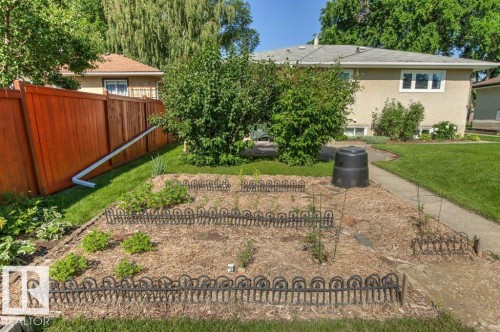 Cultivated garden bed with decorative fencing, mulched ground, and young plantings - 10235 74 Street, Edmonton, AB 