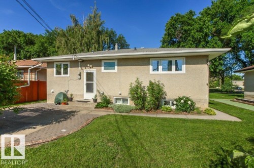 Exterior featuring stucco siding, white-framed windows, and a concrete patio - 10235 74 Street, Edmonton, AB 
