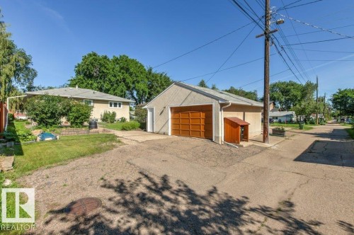 Detached garage with a paneled wood-finish door, stucco exterior, and concrete driveway - 10235 74 Street, Edmonton, AB 