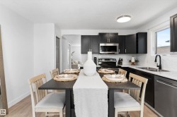 Modern kitchen featuring dark cabinetry, stainless steel appliances, white subway tile backsplash, white countertops, and wood-finish flooring - 