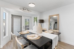 Dining area featuring wood-finish flooring, a contemporary ceiling fixture, and a bay window with multiple glass panels - 