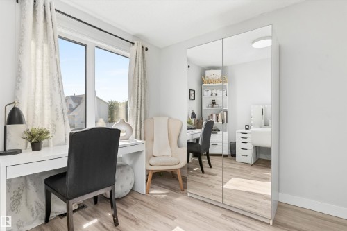 Room featuring wood-finish flooring, a large window, light-toned walls, and a built-in mirrored wardrobe - 15252 81 Street, Edmonton, AB 