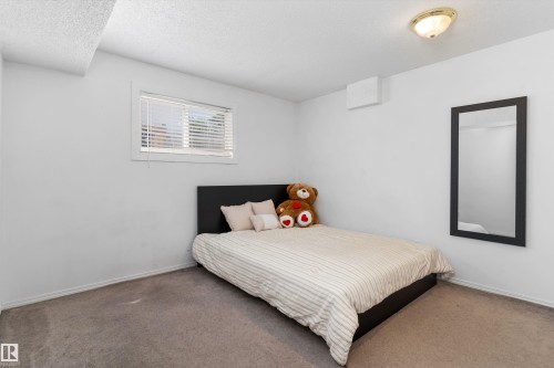 Carpeted room with a single window featuring blinds, a ceiling-mounted light fixture, and white painted walls - 15252 81 Street, Edmonton, AB 