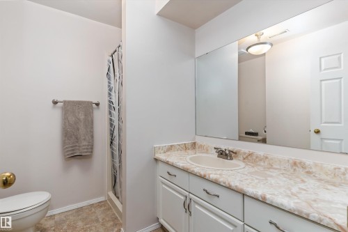 Bathroom featuring a vanity with an integrated sink, patterned countertop, and white cabinetry - 15252 81 Street, Edmonton, AB 