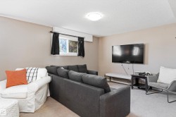 Carpeted living area featuring a wall-mounted television and a window with dark curtains - 