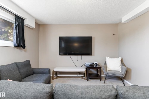 Carpeted room featuring a window with a valance, textured ceiling, and light neutral wall paint - 15252 81 Street, Edmonton, AB 