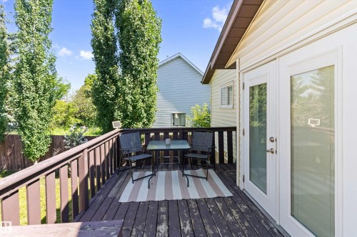 Spacious outdoor deck featuring dark wood-finish flooring, a wood railing, and white double French doors - 15252 81 Street, Edmonton, AB 