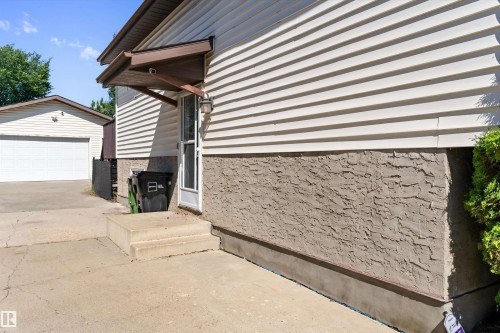 Exterior featuring horizontal siding and textured foundation, concrete steps, and an overhead entryway awning - 15252 81 Street, Edmonton, AB 