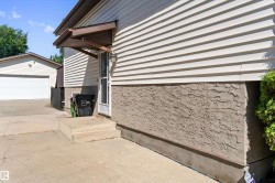 Exterior featuring horizontal siding and textured foundation, concrete steps, and an overhead entryway awning - 