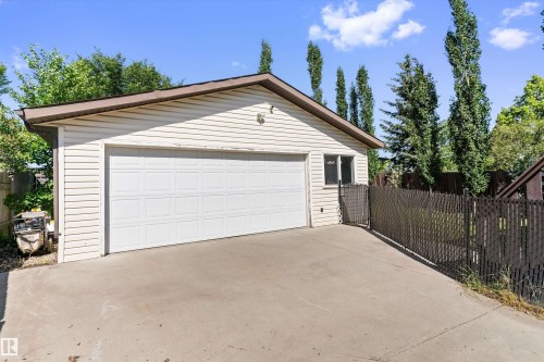 Detached garage featuring panel siding, a single panel garage door, and a brown trim roofline - 15252 81 Street, Edmonton, AB 