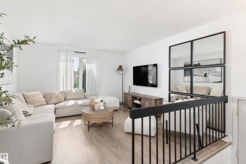 Living area featuring light wood-finish flooring, white walls, and a window with sheer curtains - 15252 81 Street, Edmonton, AB 