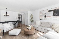 Bright interior with light wood-finish flooring, white walls, and a black metal stair railing - 