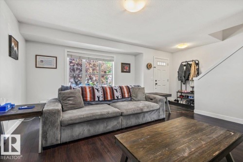 Spacious living area featuring dark wood-finish flooring, white walls, and a large window with white trim - 125 Birchwood Close, Devon, AB 