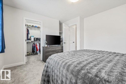 Carpeted interior space featuring a walk-in closet with built-in shelving, a dresser with storage, and a separate interior door - 125 Birchwood Close, Devon, AB 