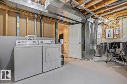 Dedicated laundry area with a white washing machine and dryer, exposed ceiling joists, and a white paneled door - 