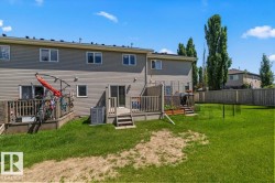 Expansive backyard featuring a manicured lawn, two elevated wood decks, and a privacy fence - 